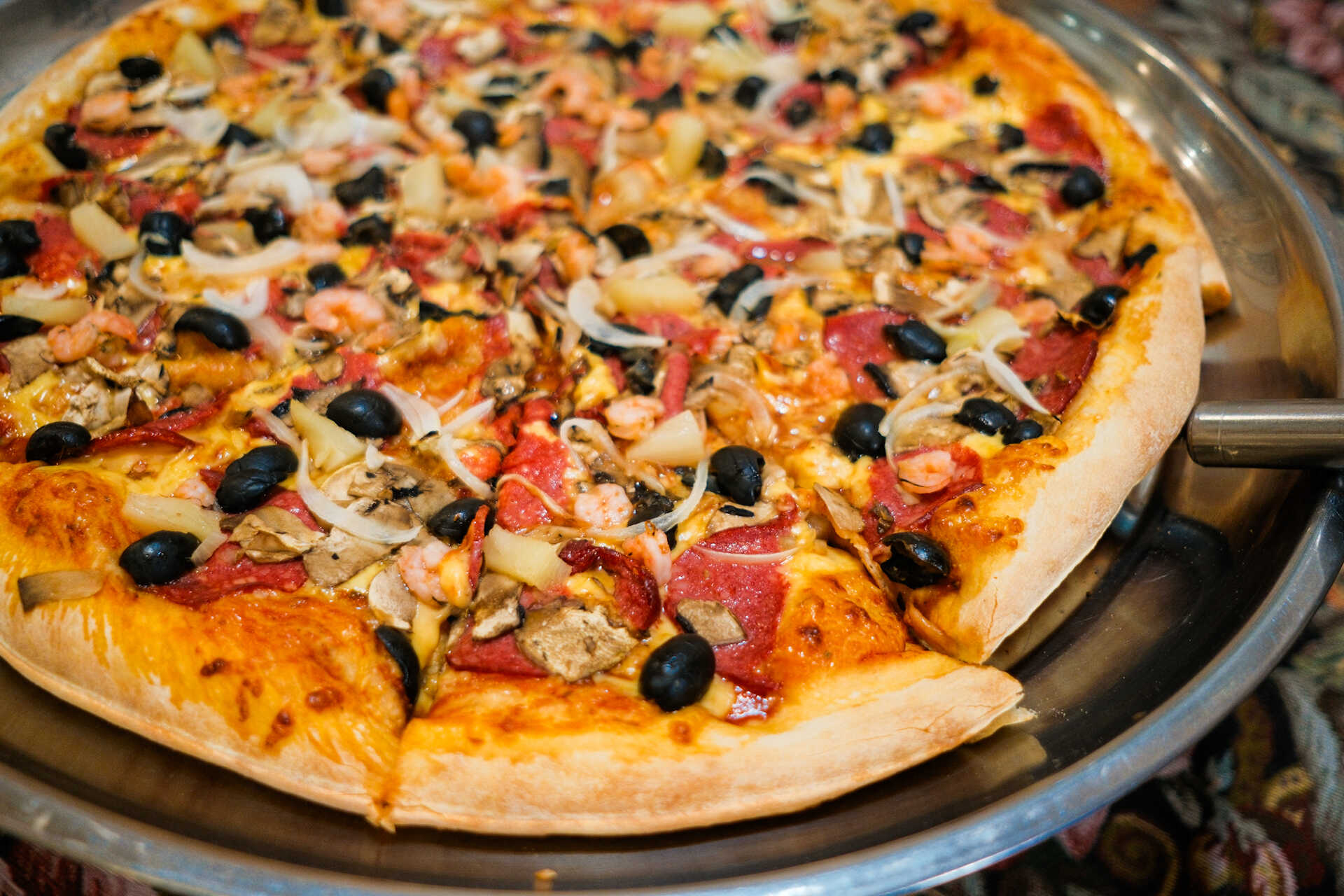 Large supreme pizza with olives and mushrooms served at Vesuvio Pizza