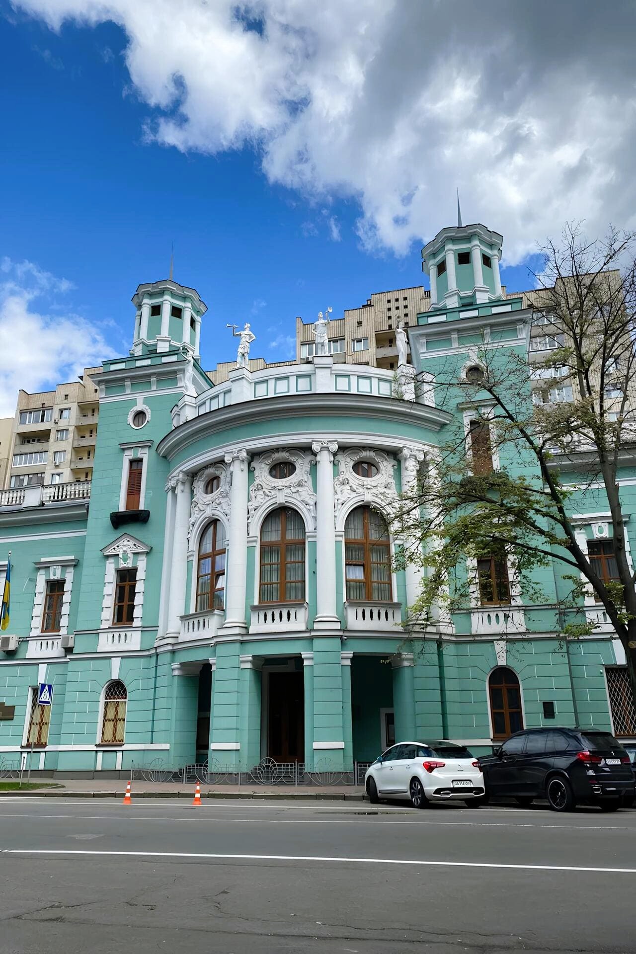 Crimean House in Kyiv - mint-green historic building with white stucco details and towers, viewed from across the street under a blue sky