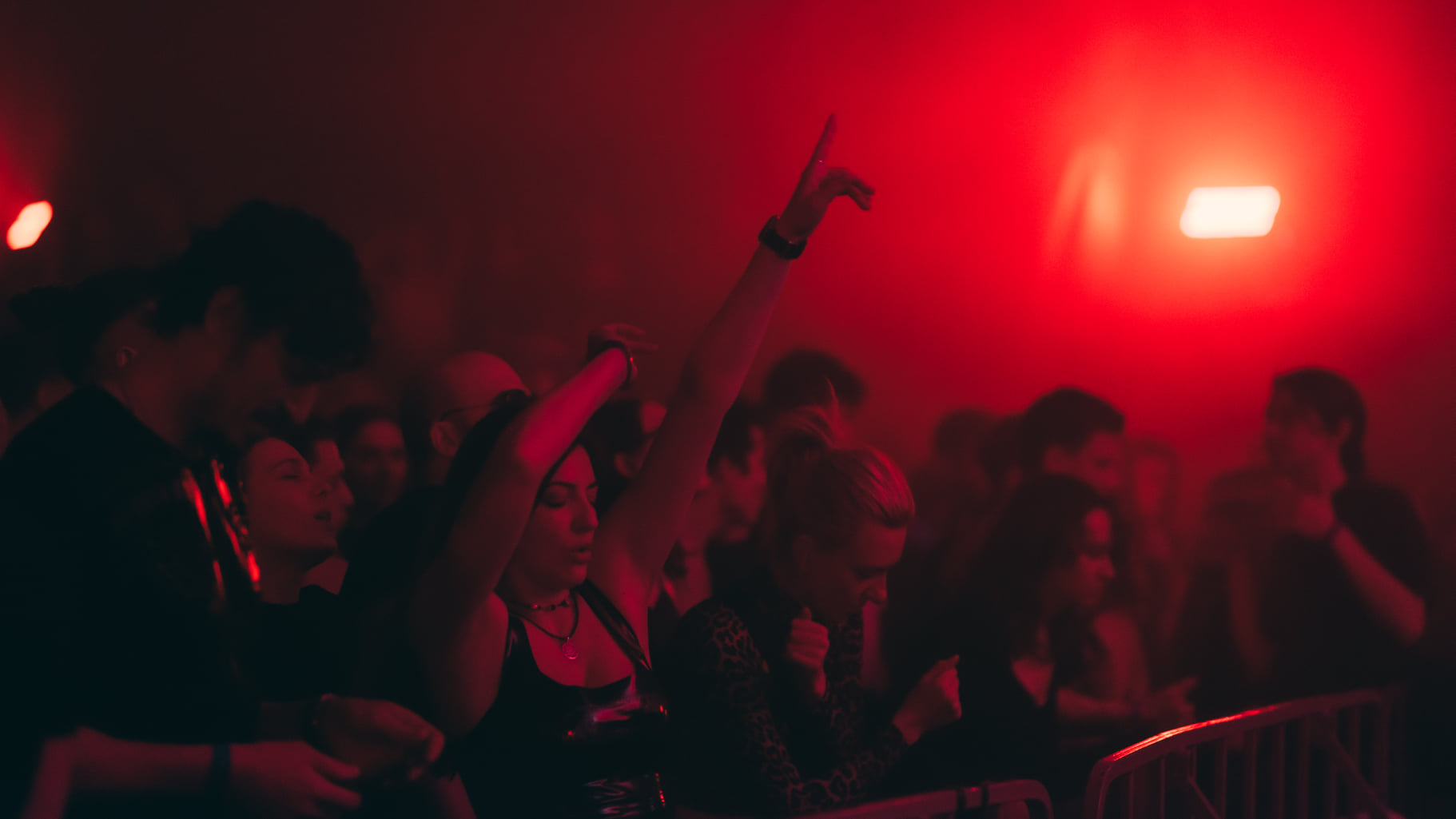 People dancing at a techno party under intense red club lighting