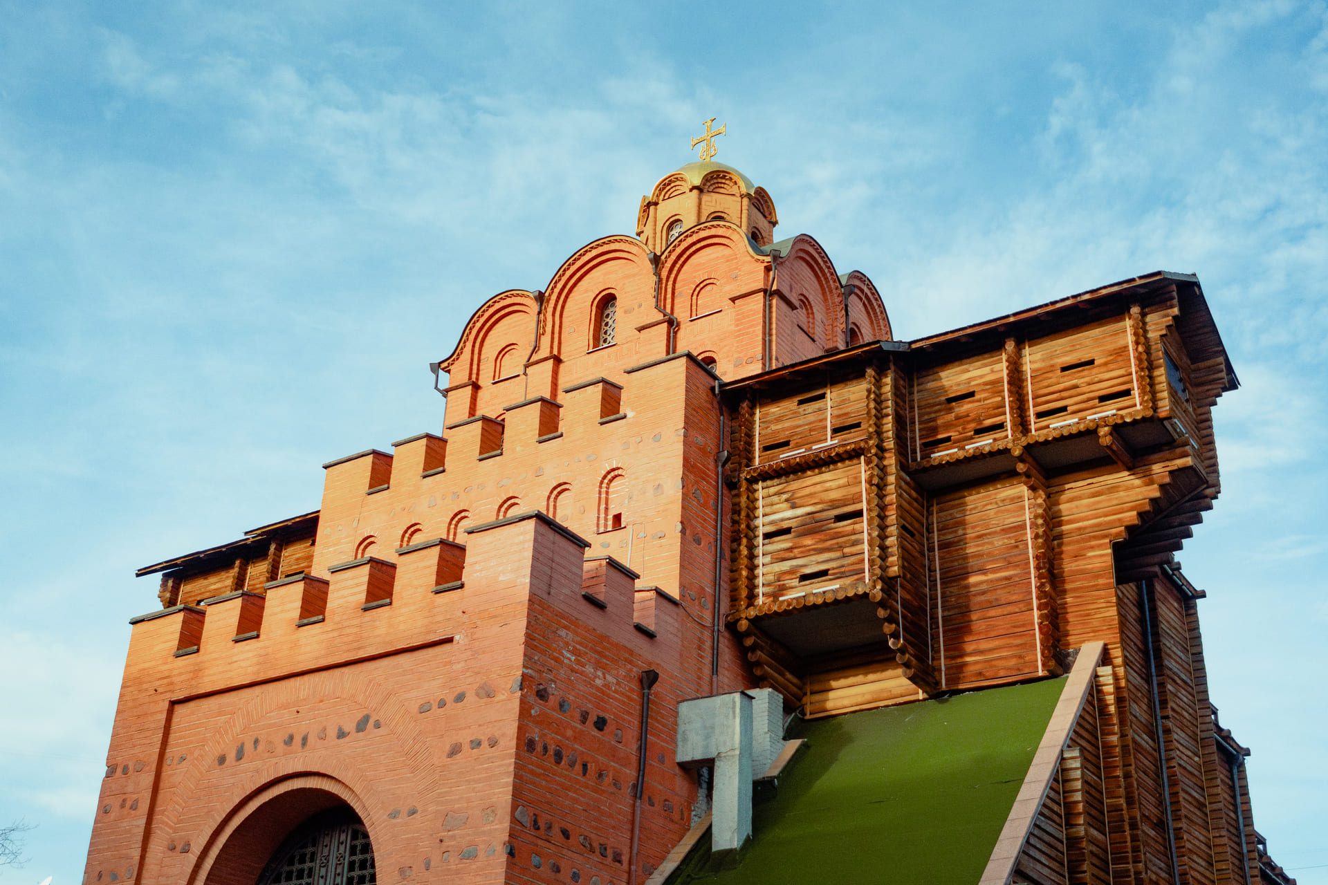 Golden Gate in Kyiv - reconstructed medieval city gate with red brick walls and a wooden fortification, viewed from below on a clear day