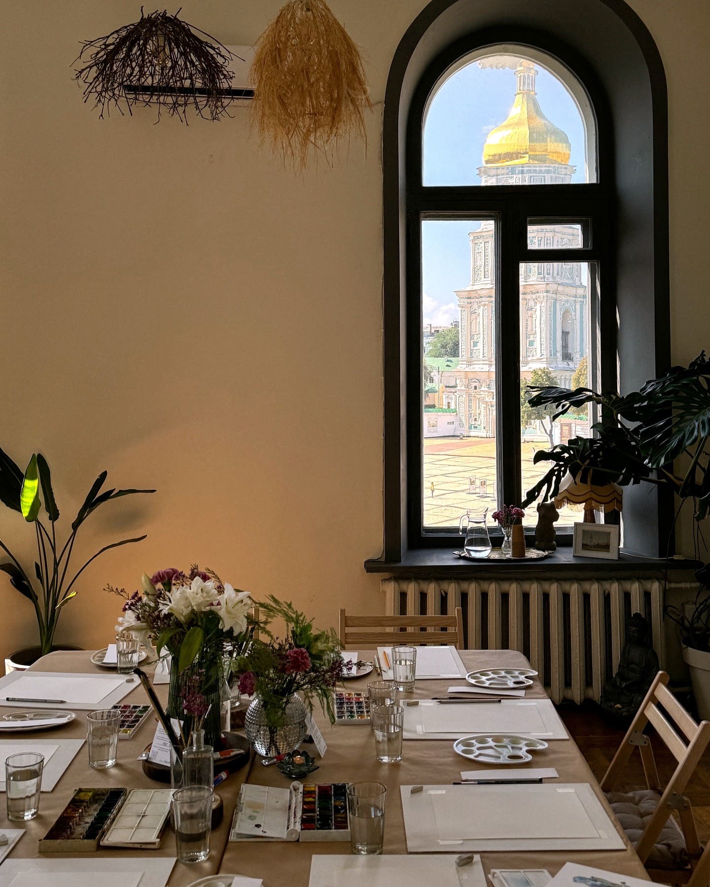 Isaeva Gallery in Kyiv – art workshop table set with paints and paper by an arched window