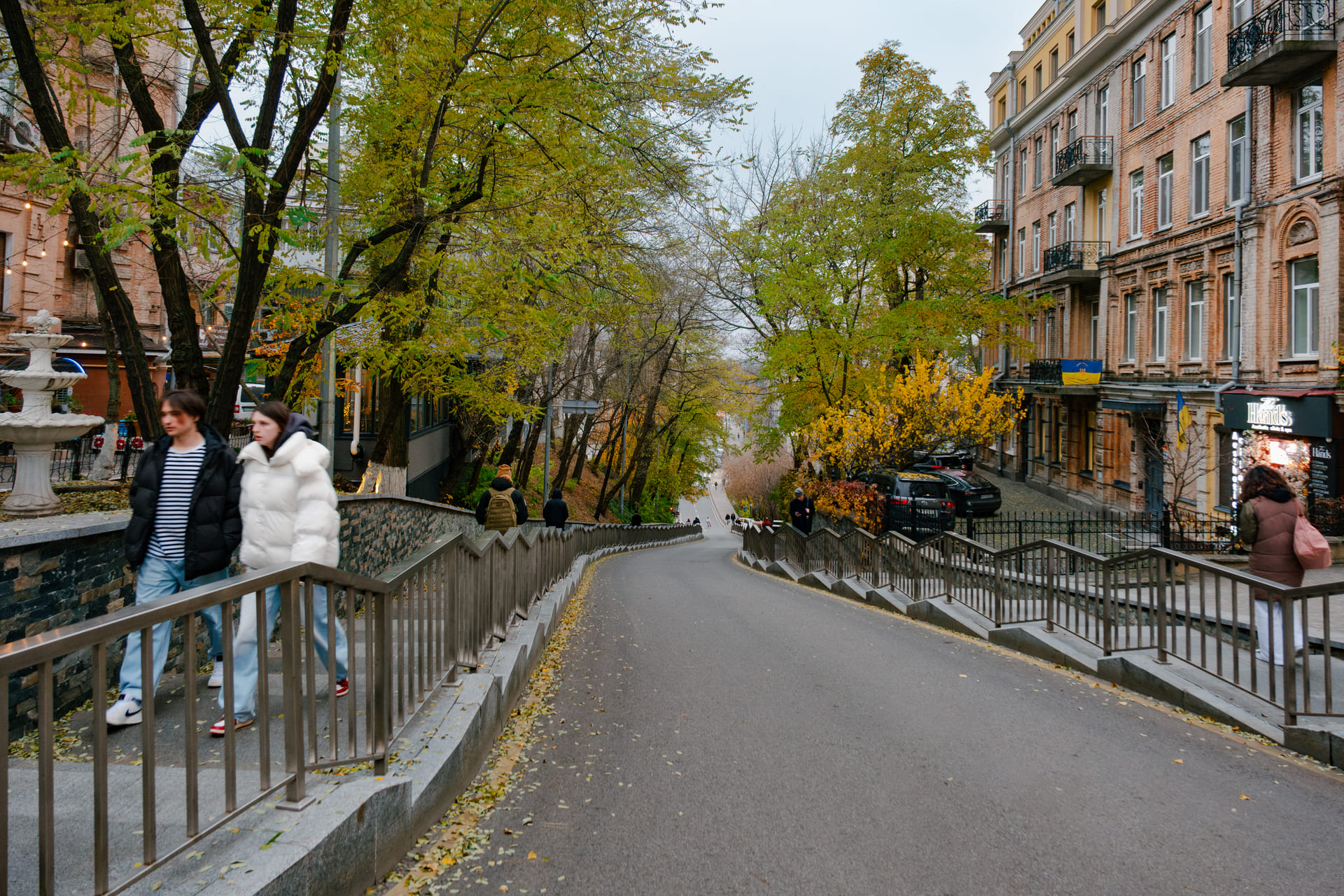 Ivan Franko Street in Kyiv- sloping city street lined with trees and historic buildings, people walking downhill in an autumn setting
