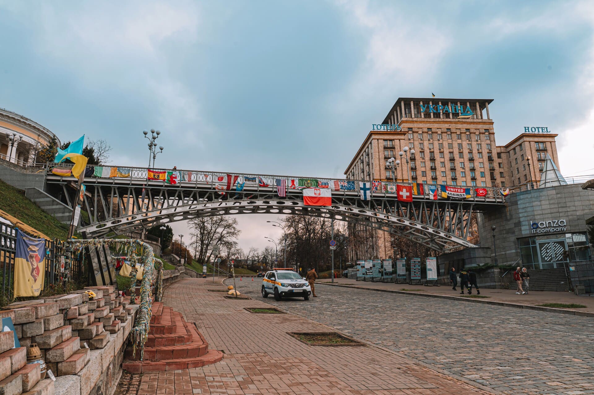 Millennium Bridge in Kyiv - pedestrian bridge decked with international flags near Hotel Ukraine