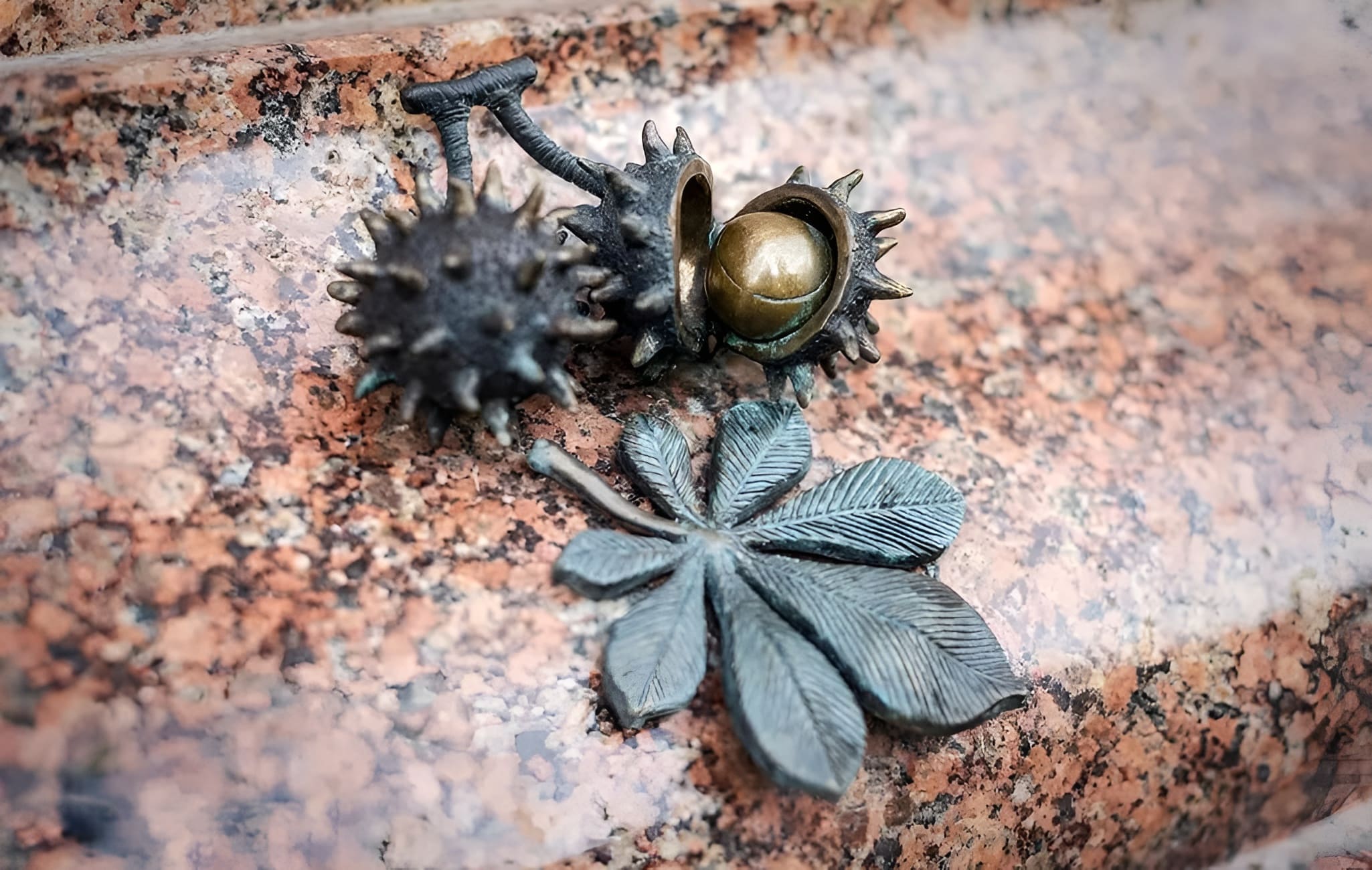 Bronze mini-sculpture of a Kyiv chestnut leaf and fruit on a stone surface