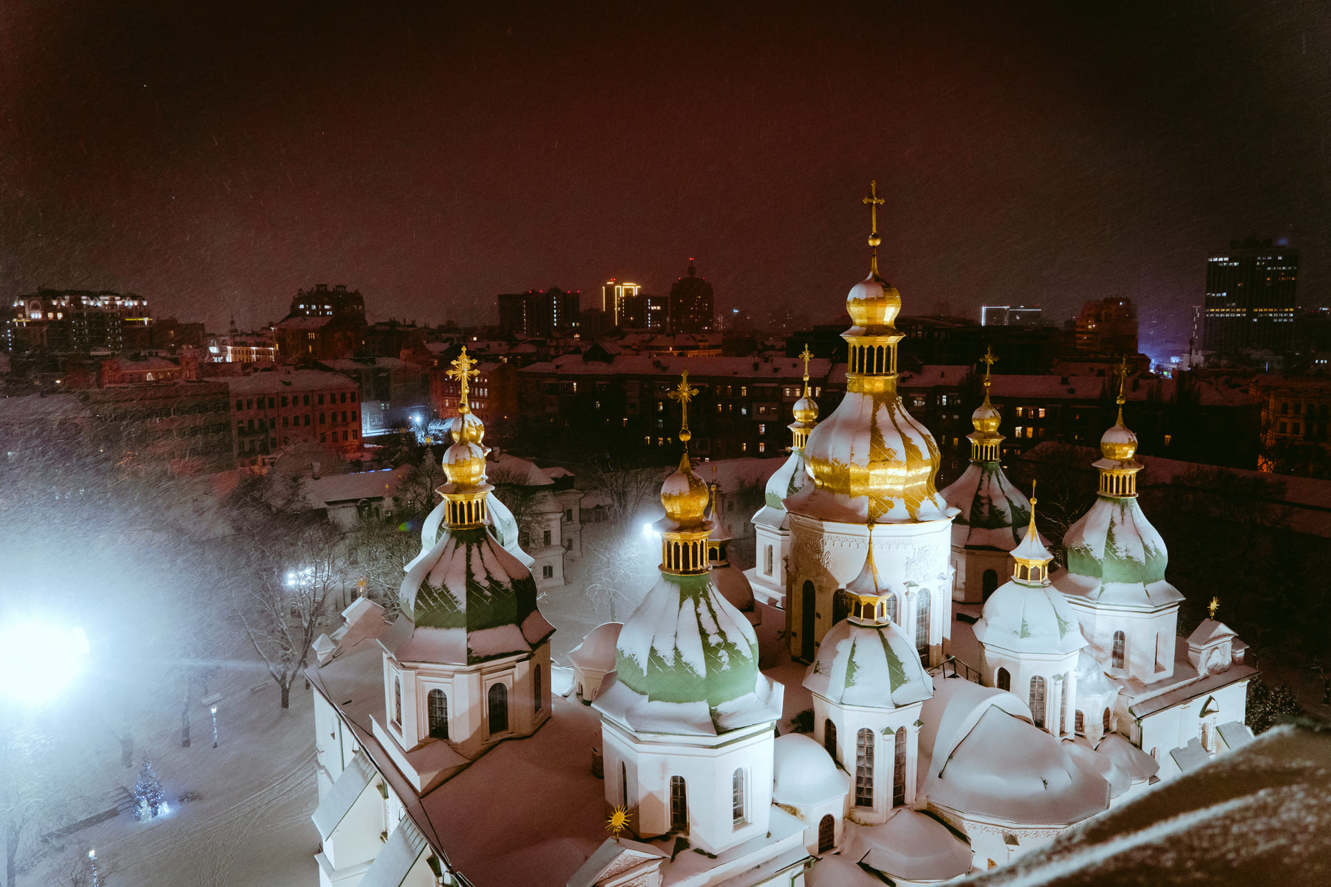 Snow-covered domes of St. Sophia Cathedral seen from above at night in Kyiv