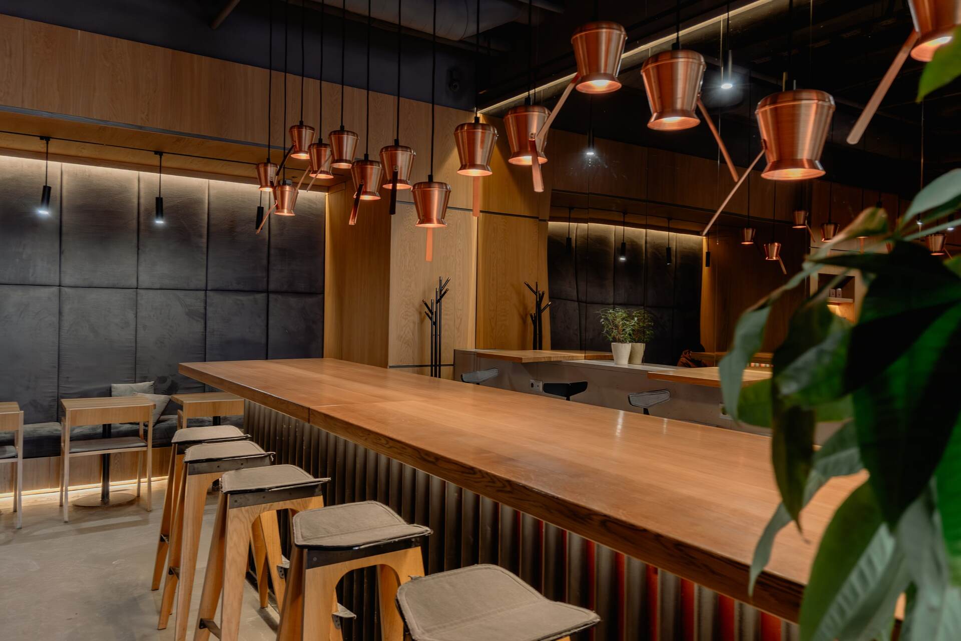 Long wooden bar counter with copper lamps in Takava coffee shop in Kyiv