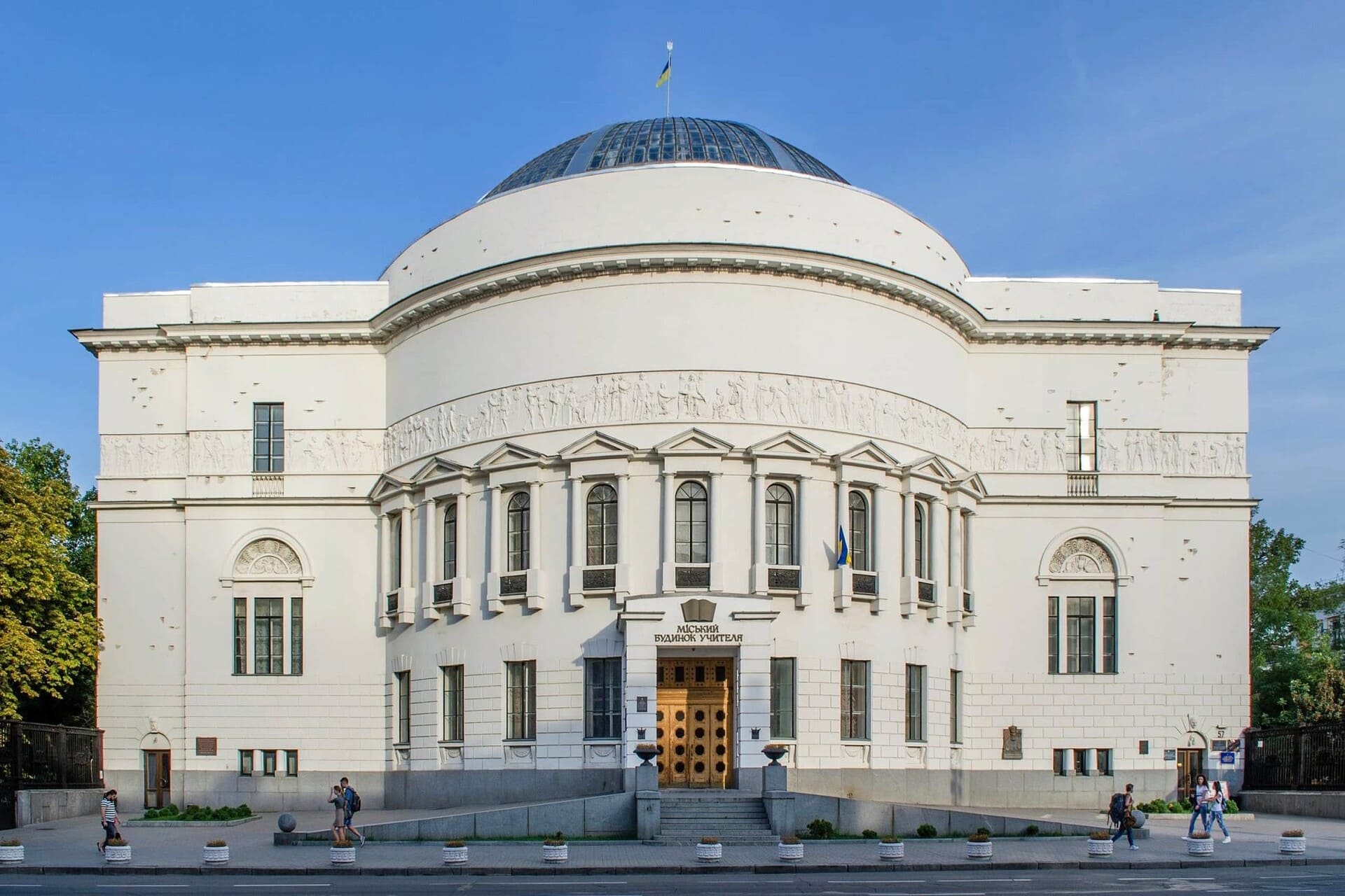 Teacher's House in Kyiv - white neoclassical building with a large glass dome and relief frieze, viewed from the front on a clear day