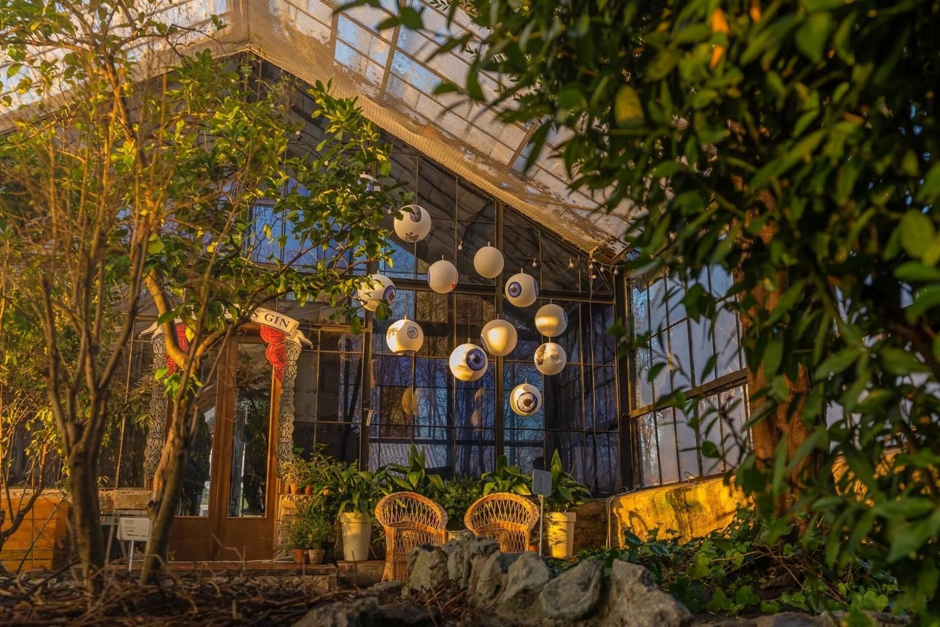 Greenhouse in Kyiv - seating area with hanging decorative eyes inside a glass greenhouse