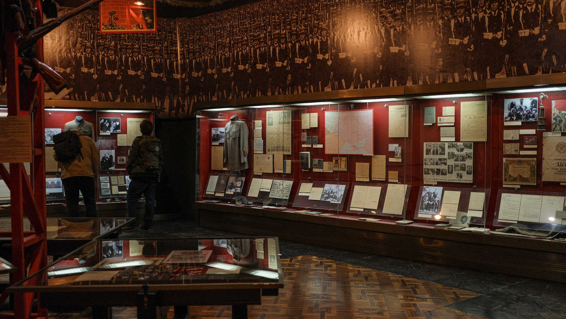 War Museum - view of the museum hall featuring red illuminated display cases and a wall mural of marching soldiers