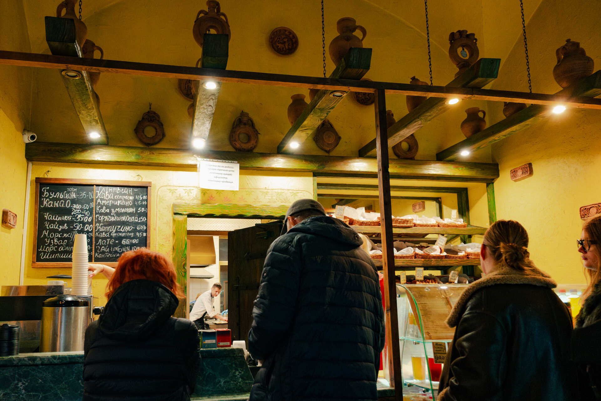 People at the counter of Yaroslava bakery with vintage decor and menu board