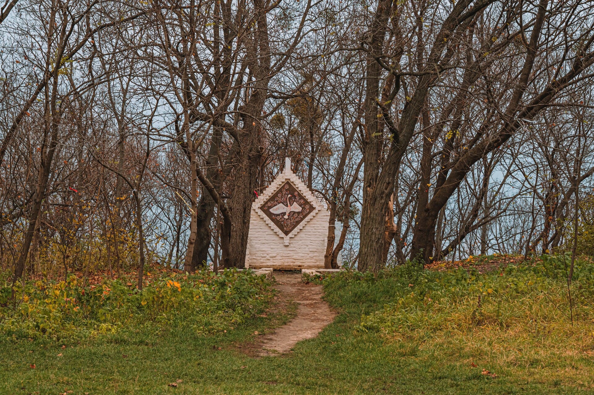 Castle Hill in Kyiv - small white brick crypt with a swan mosaic in the woods
