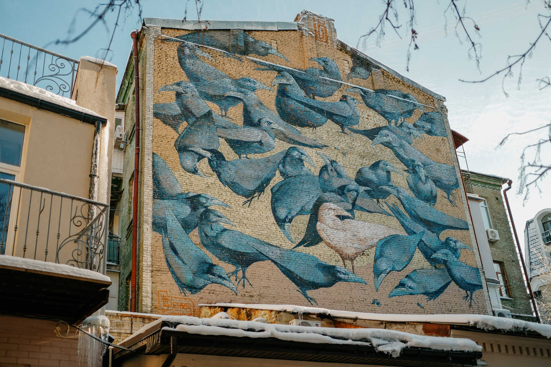 Full view of the Herald of Life crow mural on a brick wall in Kyiv