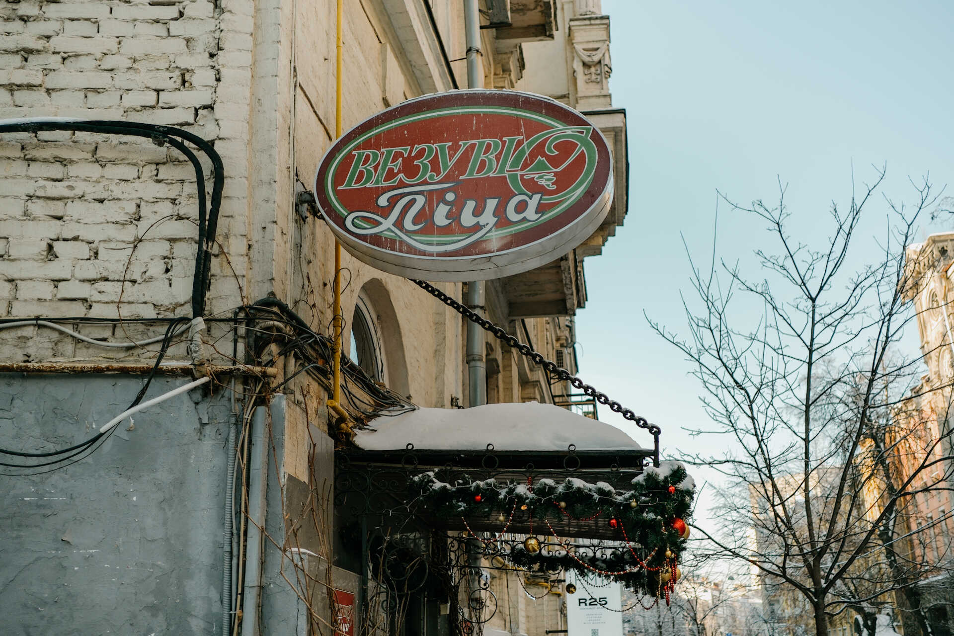 Oval Vesuvio Pizza sign on a white brick wall in Kyiv