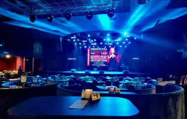 Freedom Hall in Kyiv - cozy concert hall bathed in blue light with round tables and a stage prepared for a show