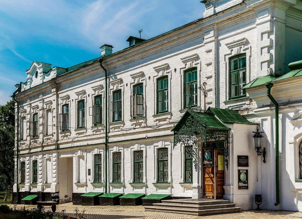 Mykola Syadristy Microminiatures Museum in Kyiv - historic white building with green framed windows and an ornate wrought-iron entrance canopy located in the Kyiv Pechersk Lavra