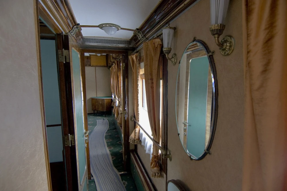 Railway Museum in Kyiv - narrow vintage train corridor lined with wood paneling, mirrors, and beige curtains evoking the atmosphere of past travel