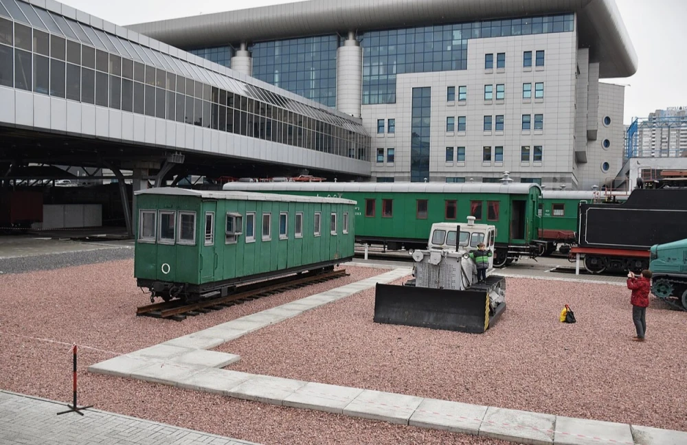 Railway Museum in Kyiv - outdoor exhibition of vintage green railway carriages parked on gravel tracks near the modern glass train station building