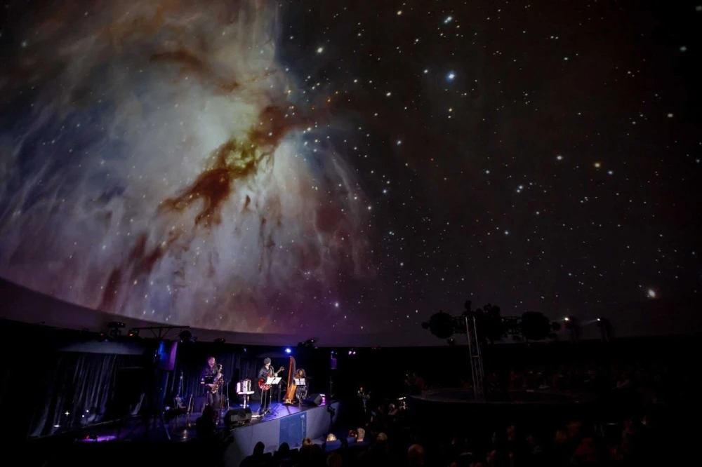 Musicians performing on stage under a dome with a nebula projection at the Kyiv Planetarium