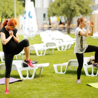 Girls doing fitness and working out on the lawn with yoga mats