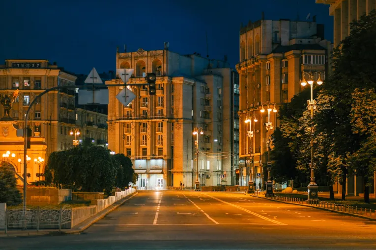 An empty illuminated street in central Kyiv at night during curfew.
