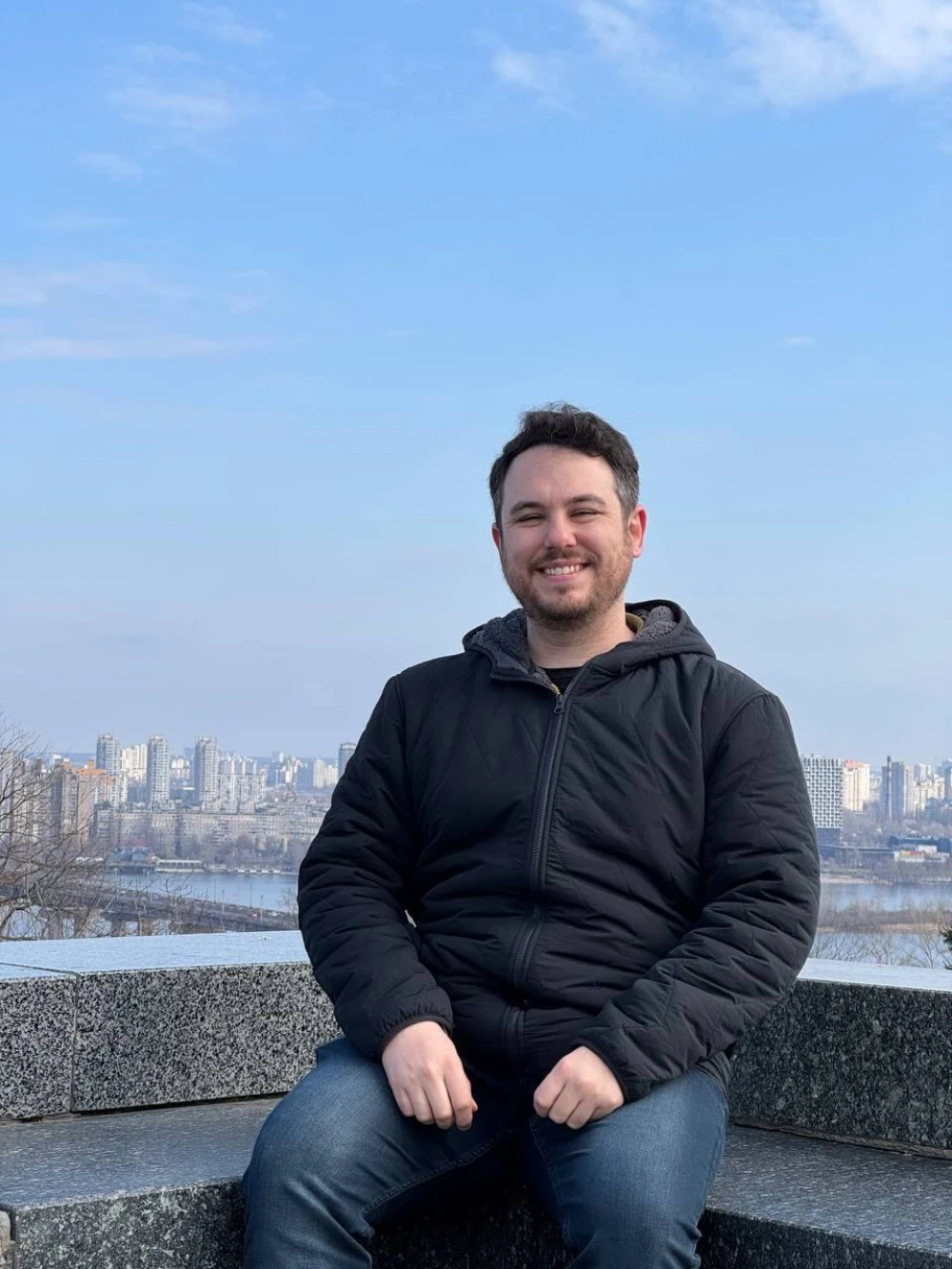 Jake McGrew is sitting against the backdrop of Kyiv