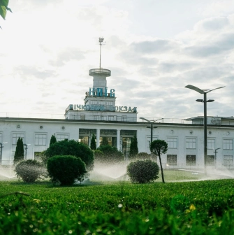 Poshtova Square in Kyiv - river station building with a tower and Kyiv sign behind green lawn