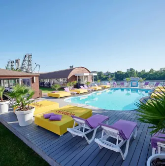 General view of the pool, sun loungers, and green plants at Sungrilla Beach