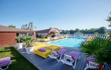 General view of the pool, sun loungers, and green plants at Sungrilla Beach