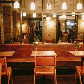 Bar Restaurant Kosatka - indoor seating area with wooden tables booth seating and exposed brick