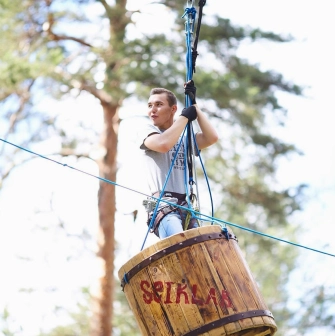 Seiklar Park in Kyiv - excited visitor gliding through the air inside a large wooden barrel suspended on cables