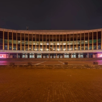 Palats Ukraina in Kyiv - panoramic night view of the illuminated curved glass facade decorated with festive pink banners