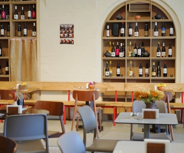 Restaurant Poltava - dining area with wooden benches and shelves stocked with wine bottles