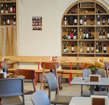 Restaurant Poltava - dining area with wooden benches and shelves stocked with wine bottles