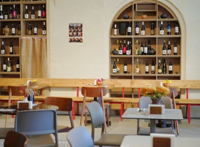 Restaurant Poltava - dining area with wooden benches and shelves stocked with wine bottles