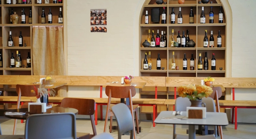 Restaurant Poltava - dining area with wooden benches and shelves stocked with wine bottles
