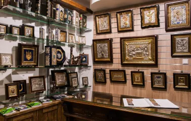 Narodnyi Dim Ukraina in Kyiv - display wall showcasing religious art with silver and gold framed icons and leather-bound books