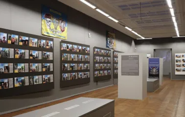 Kyivska Kartynna Halereia in Kyiv - exhibition hall with a memorial wall of photos and a military flag