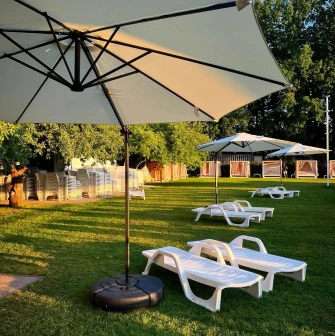White sun loungers on a sunny lawn under large umbrellas