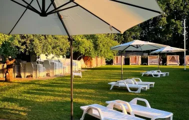 White sun loungers on a sunny lawn under large umbrellas