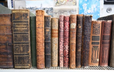 Old books with worn bindings on the shelf of a flea market near Pochaina in Kyiv