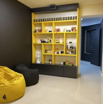 Muzei u Temriavi in Kyiv - bright yellow shelving unit displaying souvenirs and merchandise in a cozy reception area with bean bags