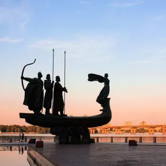 Monument to the Founders of Kyiv at sunset - dramatic silhouette over the Dnipro River and city skyline