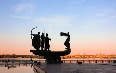 Monument to the Founders of Kyiv at sunset - dramatic silhouette over the Dnipro River and city skyline