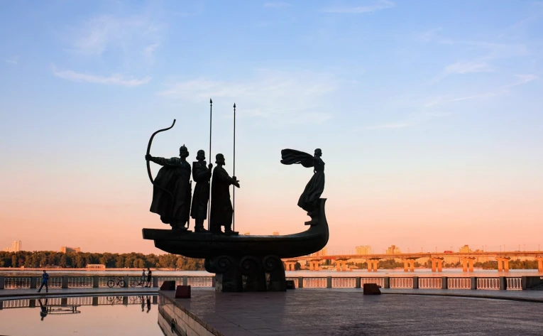 Monument to the Founders of Kyiv at sunset - dramatic silhouette over the Dnipro River and city skyline