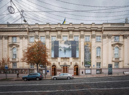 Teatr Lesi Ukrainky in Kyiv - grand historic facade of the theater featuring massive beige columns and a Ukrainian flag on the roof