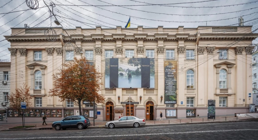 Teatr Lesi Ukrainky in Kyiv - grand historic facade of the theater featuring massive beige columns and a Ukrainian flag on the roof