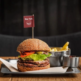 The Burger - close-up view of a signature New York burger served with fries and sauce