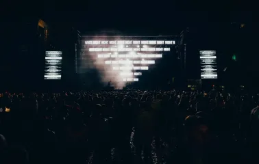 Art-zavod Platforma in Kyiv - dark silhouette of the crowd facing the stage illuminated by blinding white digital text at night