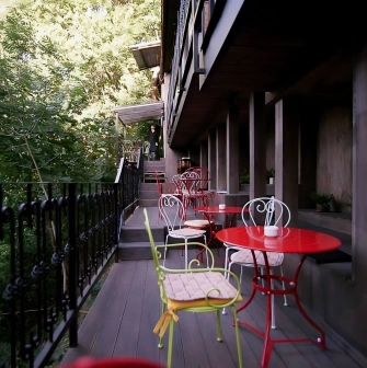 Restaurant Kanapa - narrow outdoor terrace with small tables and chairs surrounded by greenery