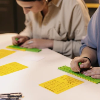 Muzei u Temriavi in Kyiv - close-up of visitors learning to write Braille using a stylus and slate during an educational workshop